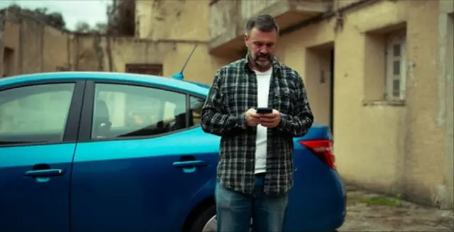 Man checking the ProCam dash cam app on his phone beside a car